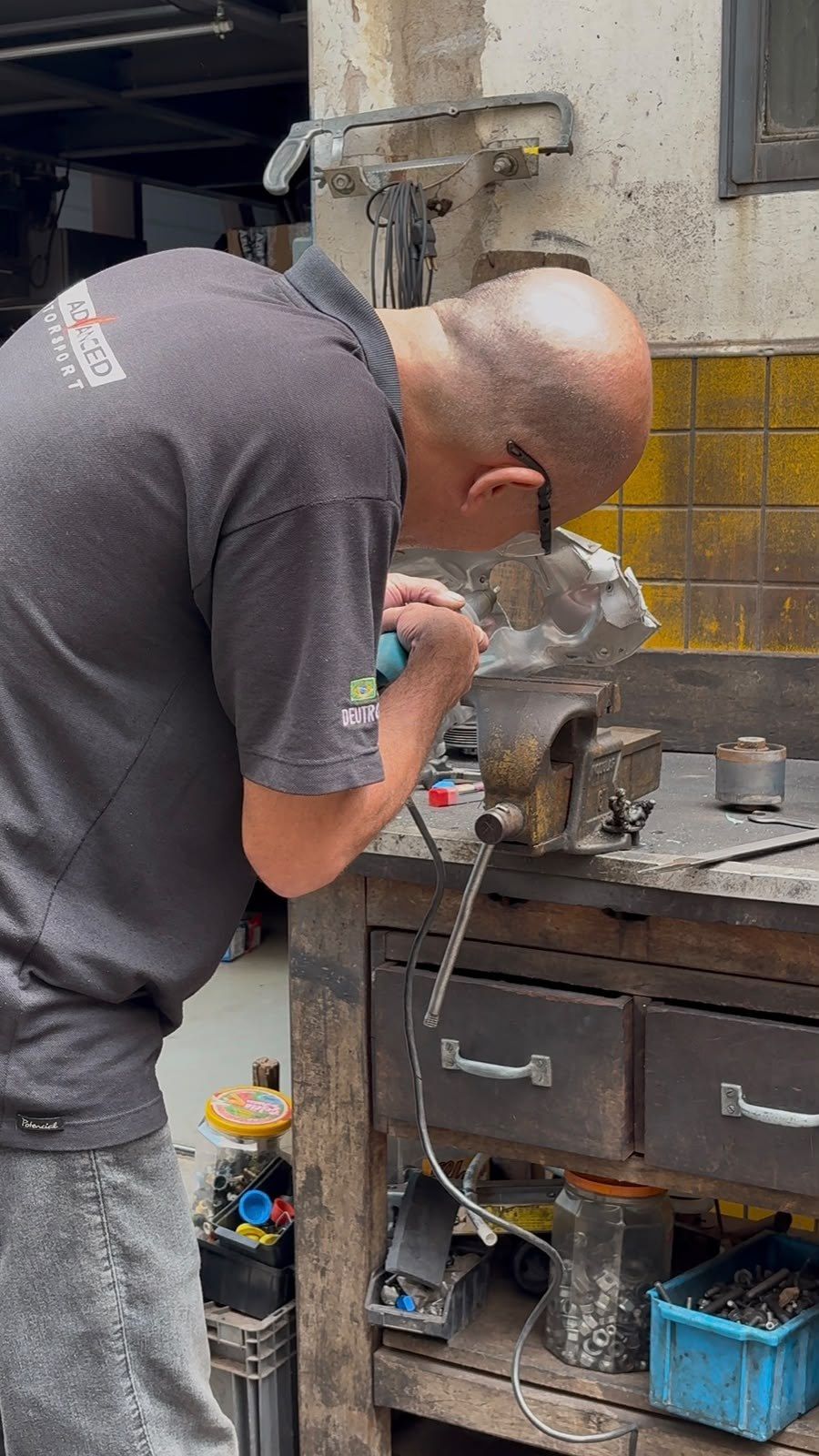 Profissional da Advanced trabalhando na bancada da oficina, com ferramentas e peças ao redor.